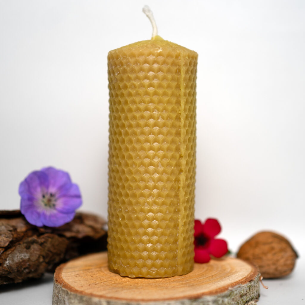 Handgegossene Bienenwachskerze mit Wabenstruktur auf Holzscheibe